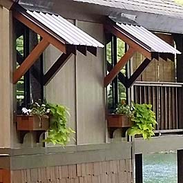 brown window boxes on lake house with bahama style window roof