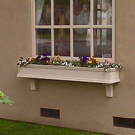 long beige window box on stucco with two support brackets